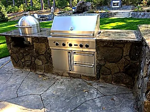 Fort Worth outdoor kitchen with carved rock surround, built-in grill and kamado smoker on a stamped concrete patio