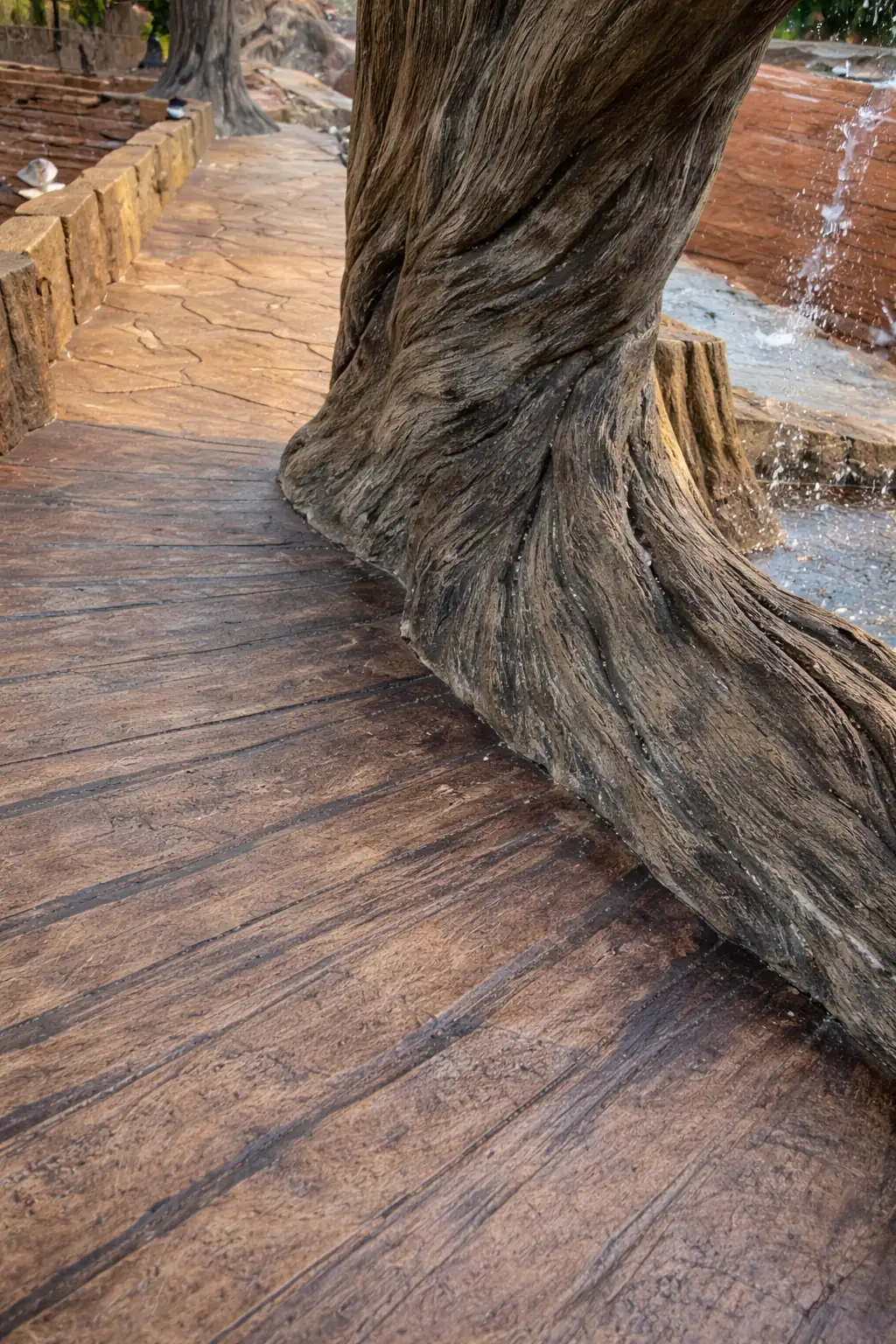 Hand-carved concrete deck with a wood-plank texture curving around a carved tree trunk
