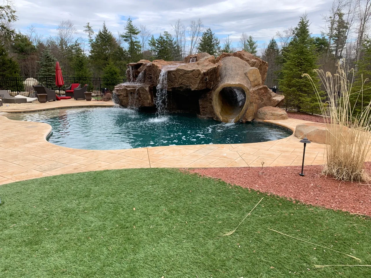 Pool grotto with a carved rock slide and waterfall built onto a freeform pool
