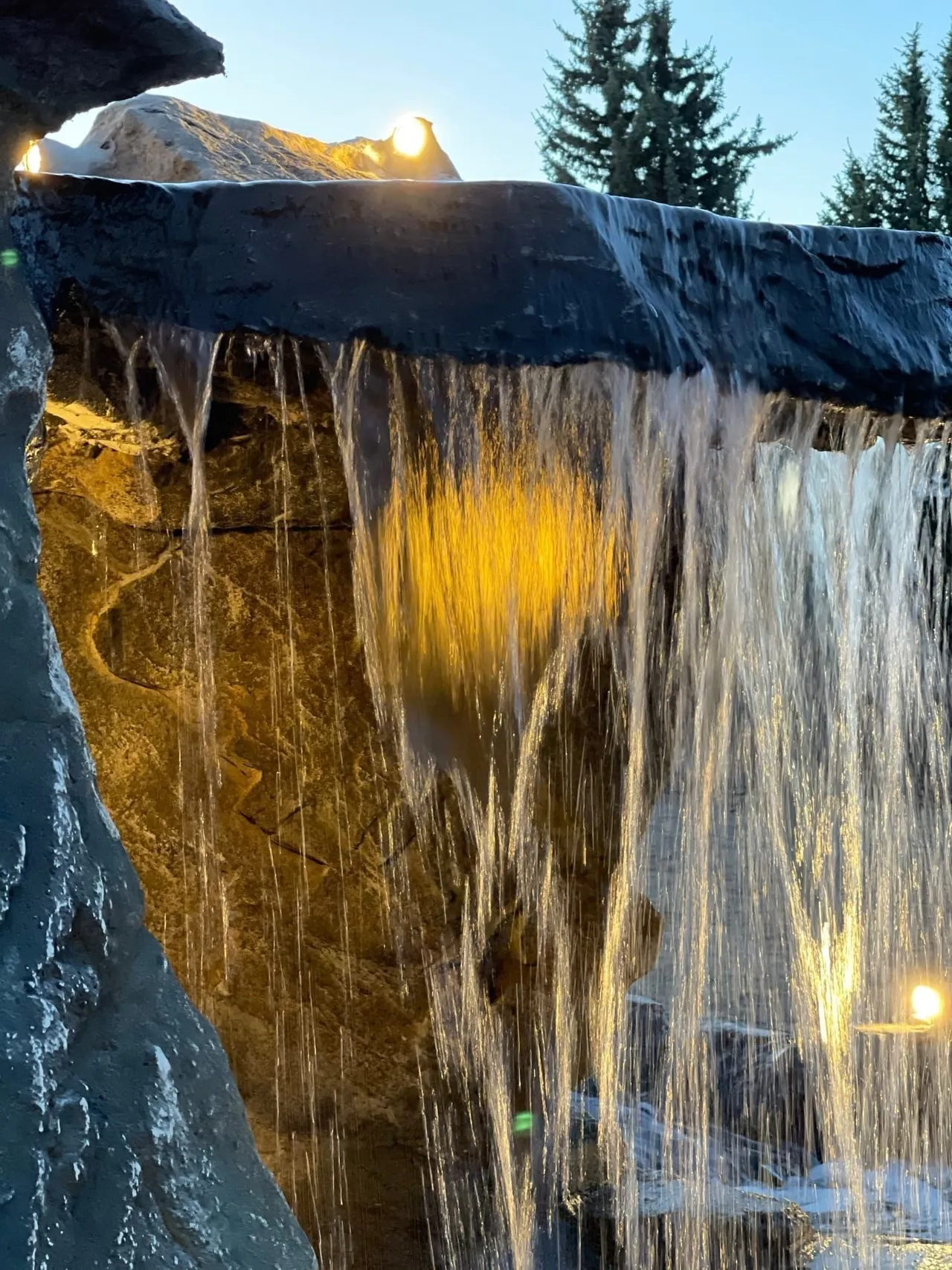 Illuminated hand-carved GFRC boulder waterfall spilling into a natural-look pond in McKinney Texas