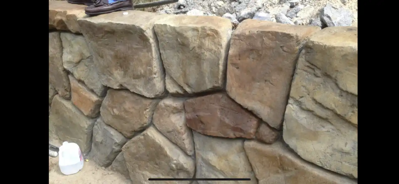 Hand-carved concrete retaining wall holding a sloped backyard grade in Rockwall TX