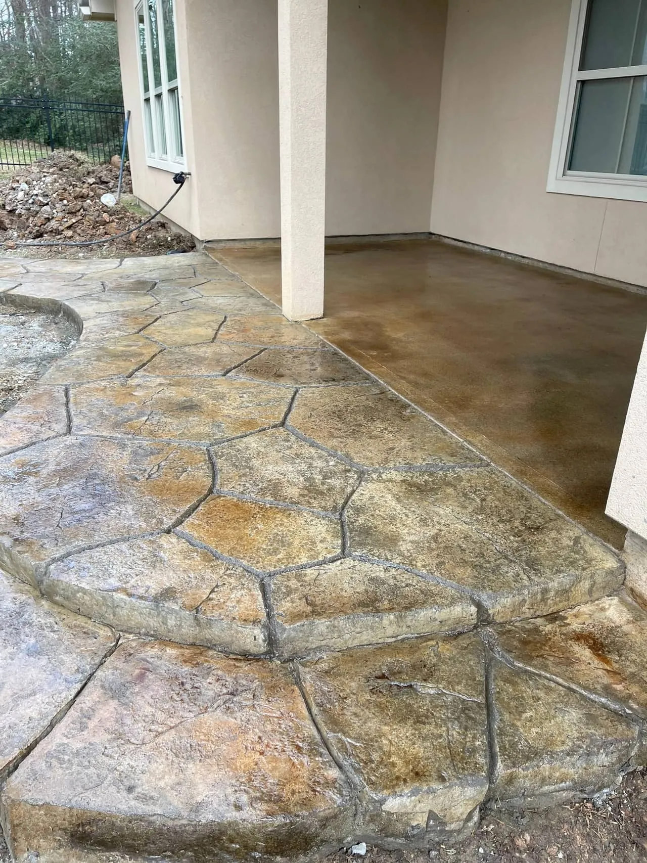 Stamped flagstone-pattern concrete patio extension beside a stained porch slab