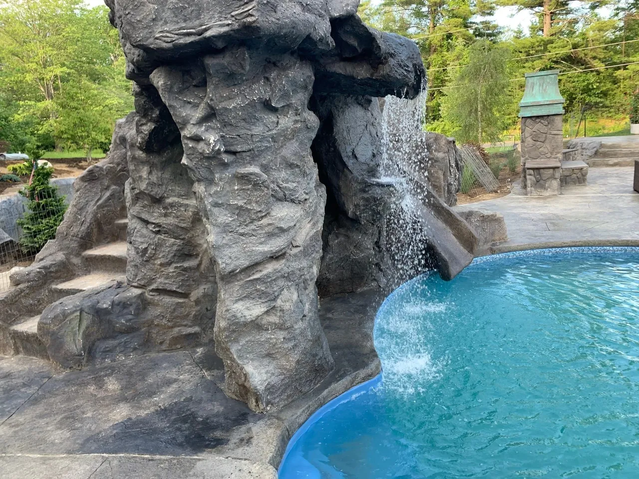 Hand-carved GFRC waterfall and slide feature built for a pool, the kind of project we install on Aledo properties